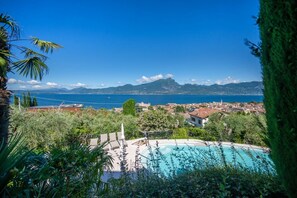 Ein Pool mit Blick auf das Meer und die Berge, umgeben von Grün.