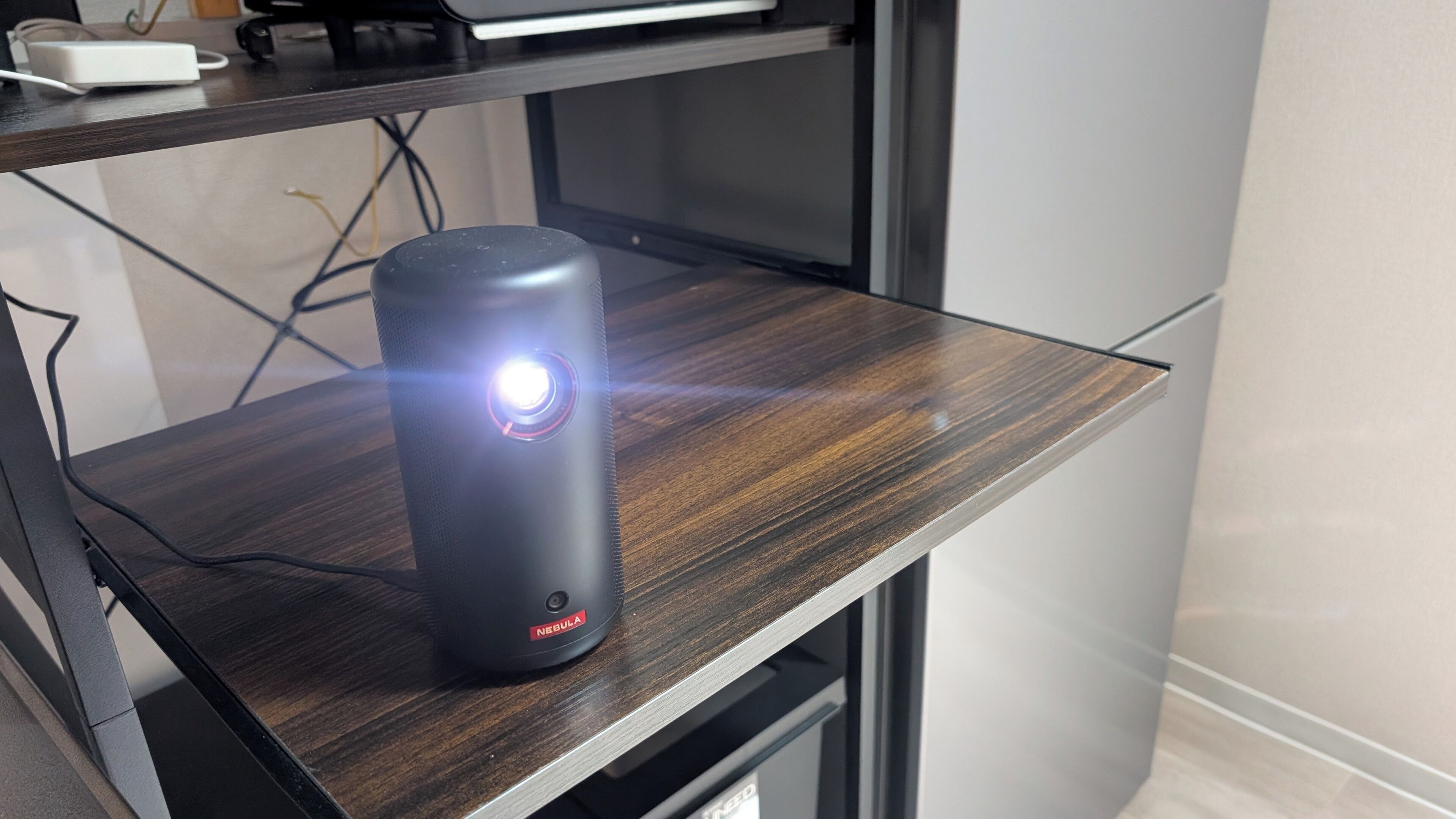Un altavoz sobre un escritorio de madera con un monitor al fondo.