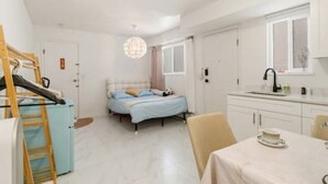 Een slaapkamer met een bed, een nachtkastje, een raam en een badkamer met een wastafel.