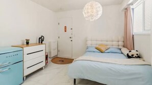 Een slaapkamer met een bed, een bureau, een stoel, een deur en een raam.
