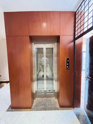 An elevator with a digital display, a wooden paneling design, and a glass door. - Corporate Hotel Shivpuri (Shivpuri)