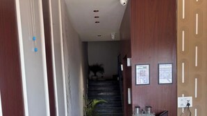 Zona de recepción de un hotel con un mostrador, una escalera y una planta en maceta.
