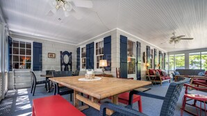 Une pièce spacieuse avec une grande table en bois, plusieurs chaises et un ventilateur de plafond.