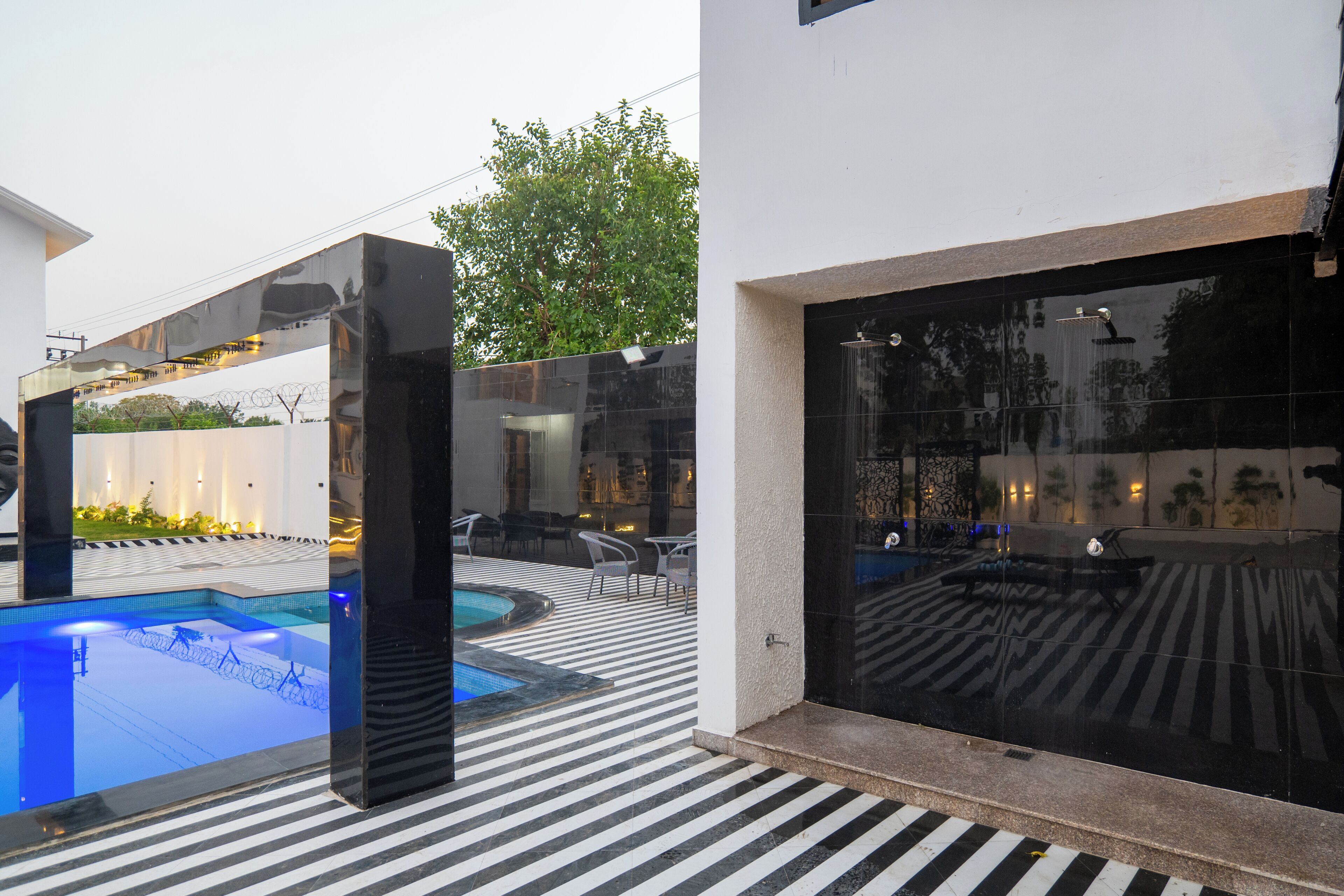 Un área de piscina moderna al aire libre con cerramiento de vidrio, un jacuzzi independiente y suelo con diseño.