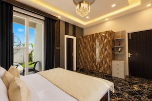A hotel room with a bed, a wardrobe, a desk, and a balcony with a view. - ELIVAAS Signature Raj Farms | 3 BHK Villa with Pvt Pool (Gurugram)