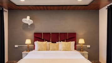 Habitación de hotel con una cama grande, dos lámparas de noche, un cabecero rojo y un ventilador de techo.