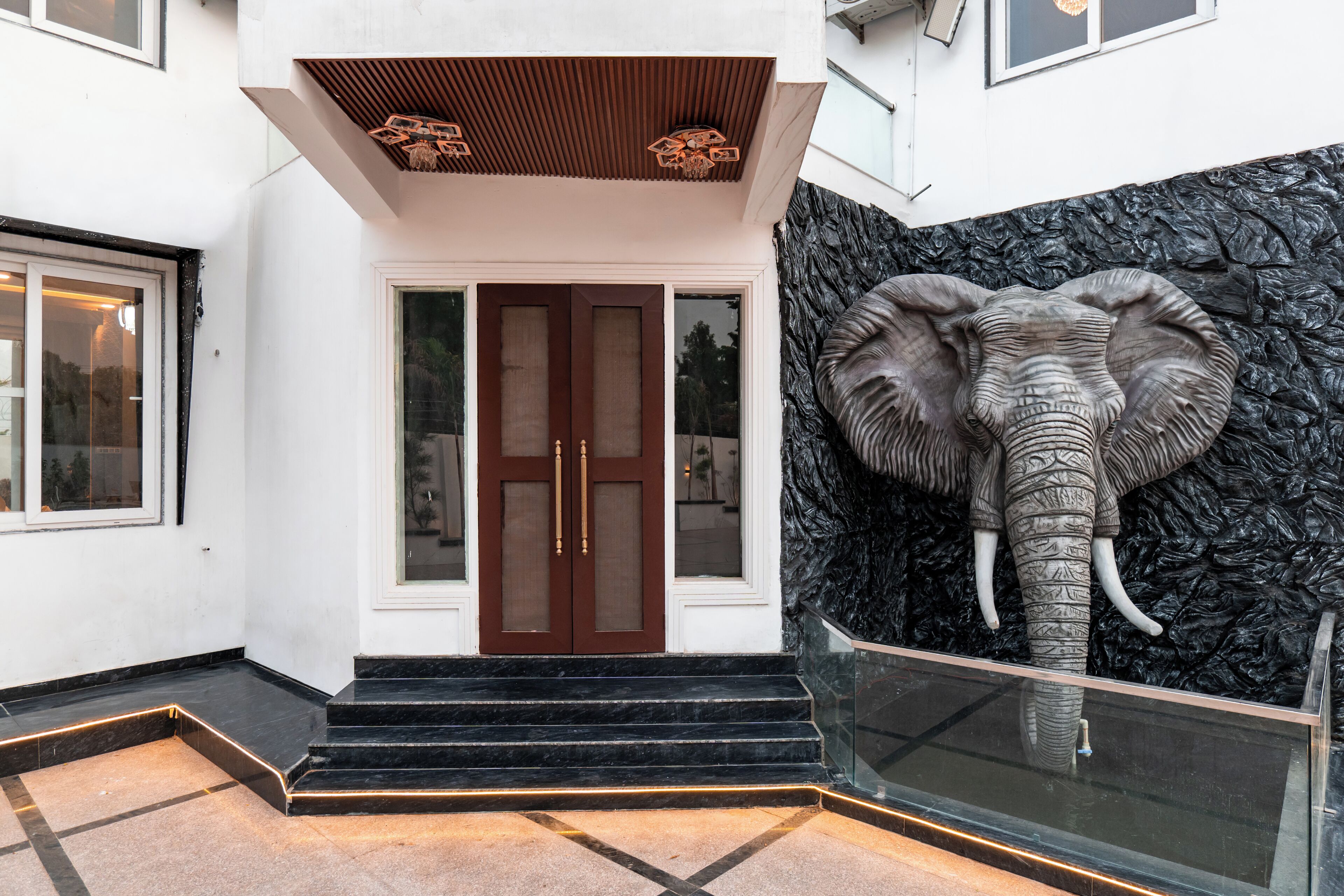 Une entrée d’immeuble ornée d’une grande sculpture d’éléphant, dotée d’un plafond en bois et d’une rambarde en verre.