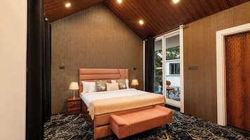Un dormitorio con cama, mesitas de noche, un banco y vistas al exterior.