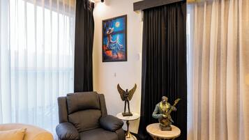 Una habitación con un sillón de cuero negro, una mesita redonda con una estatua y un cuadro en la pared.