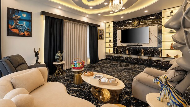 A modern living room with a sofa, armchair, coffee table, and a TV. - ELIVAAS Signature Raj Farms | 3 BHK Villa with Pvt Pool (Gurugram)