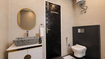 Et badeværelse med vask, spejl, toilet og bruser.