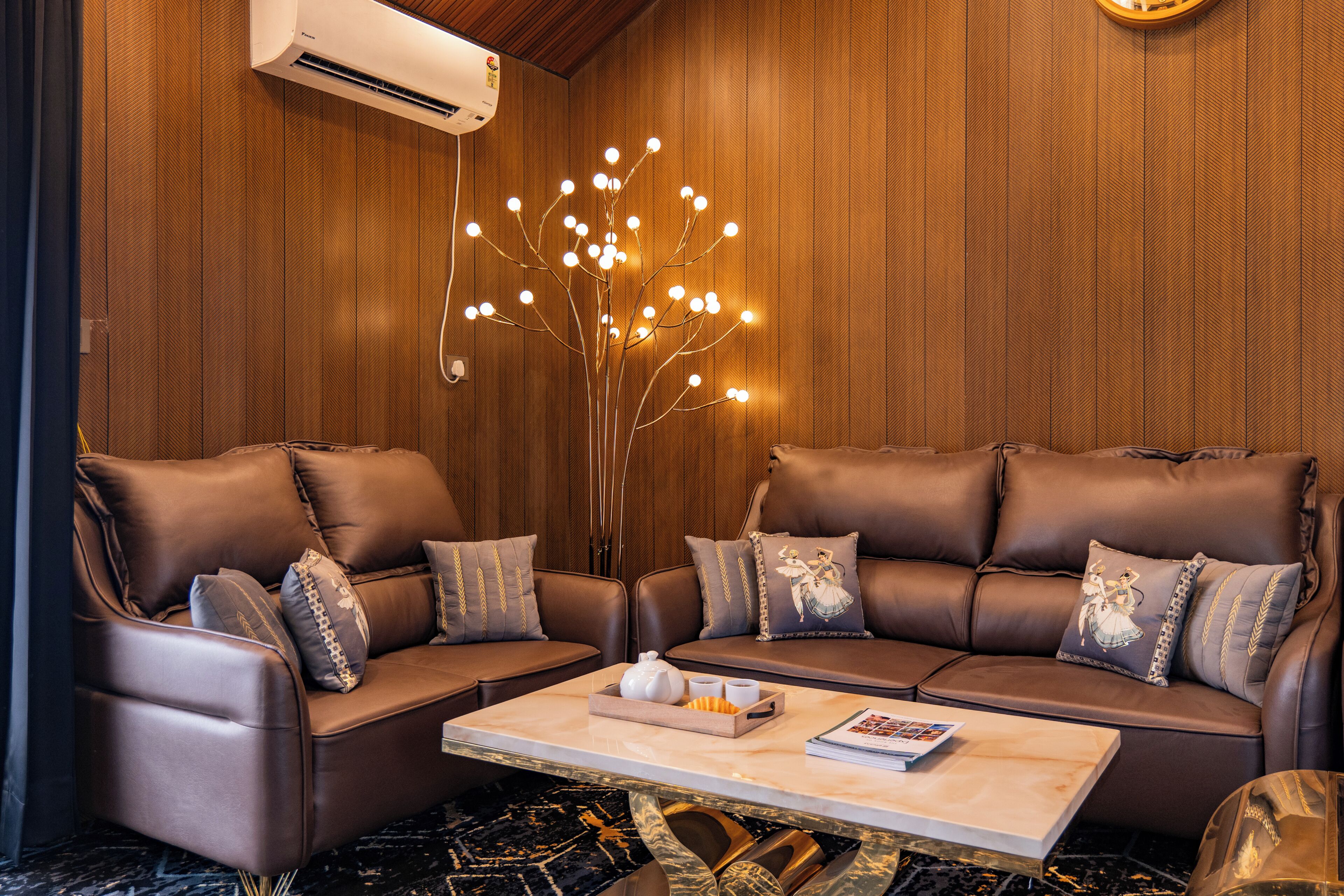 A modern living room with leather sofas, a marble coffee table, and a unique light fixture.