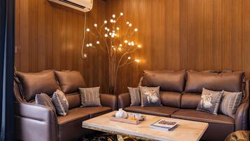 A modern living room with leather sofas, a marble coffee table, and a unique light fixture.