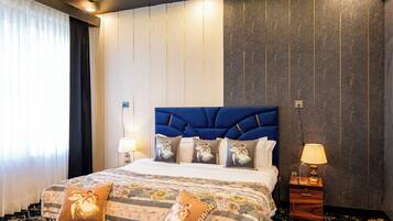 Una habitación de hotel con una cama grande, dos mesitas de noche con lámparas, un cabecero y una colcha estampada.