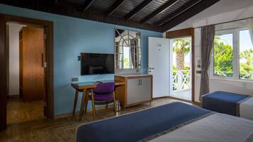 Una stanza con un letto, una scrivania con una sedia, una televisione, un armadio e un balcone con vista sul verde.