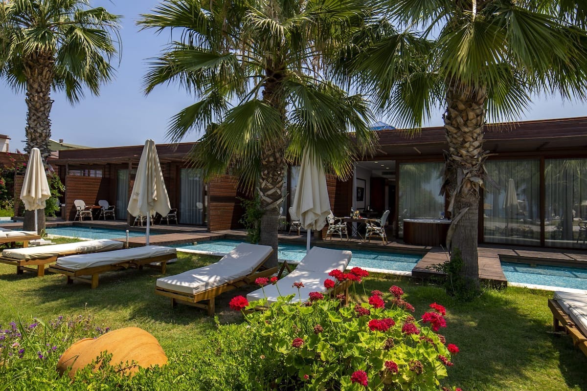 A pool area with lounge chairs, umbrellas, and a hot tub.