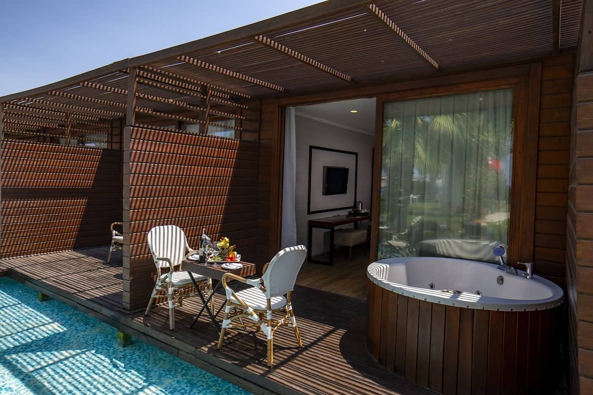 A modern outdoor deck with a hot tub, seating area, and a view of the pool.