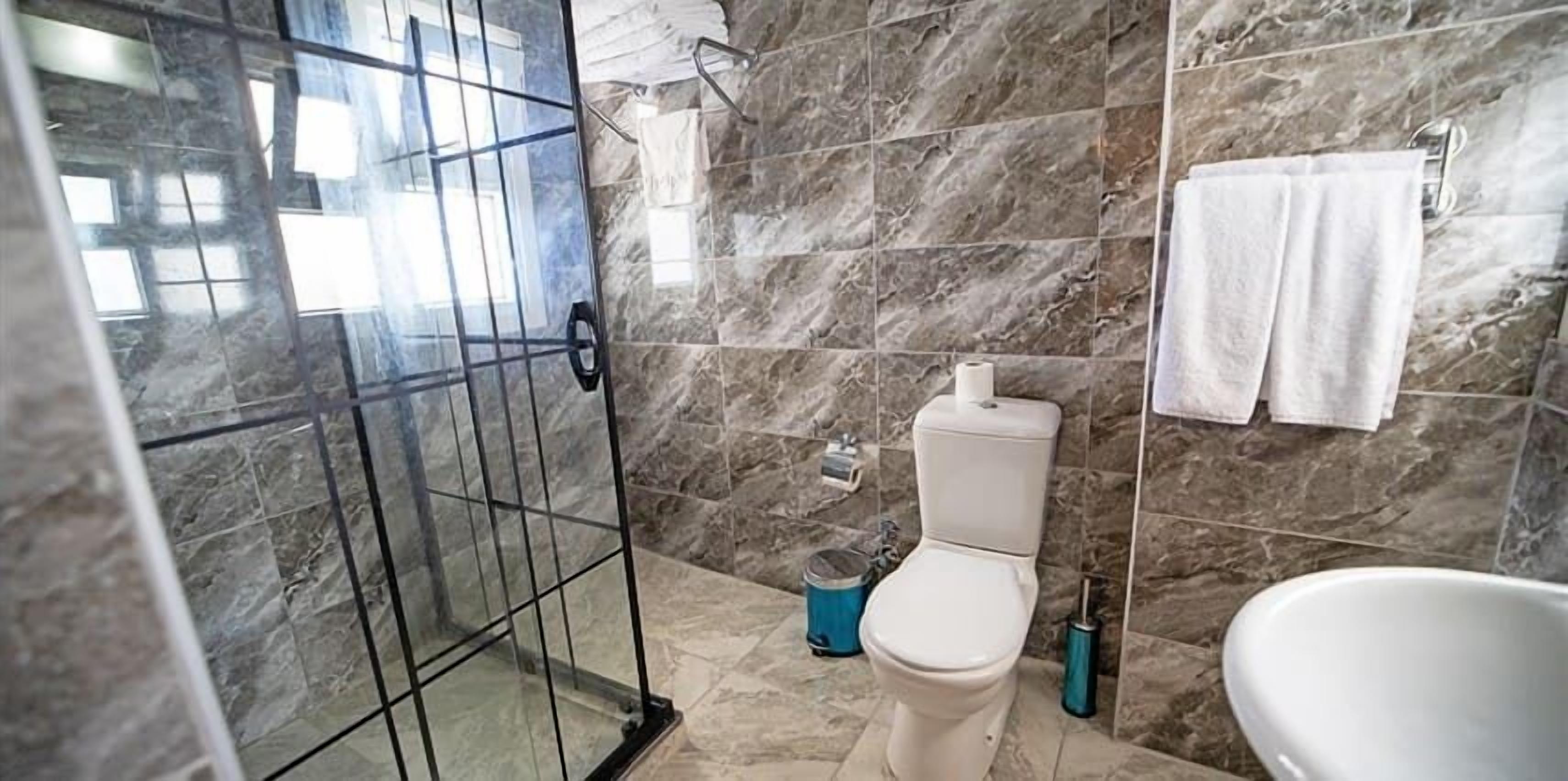 Une salle de bain avec une douche à parois de verre, des toilettes et une baignoire.