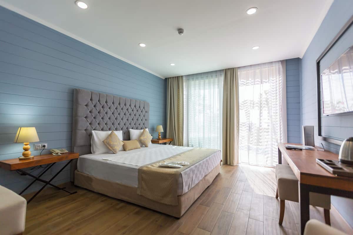 A hotel room with a bed, bedside tables, a desk, and a chair.
