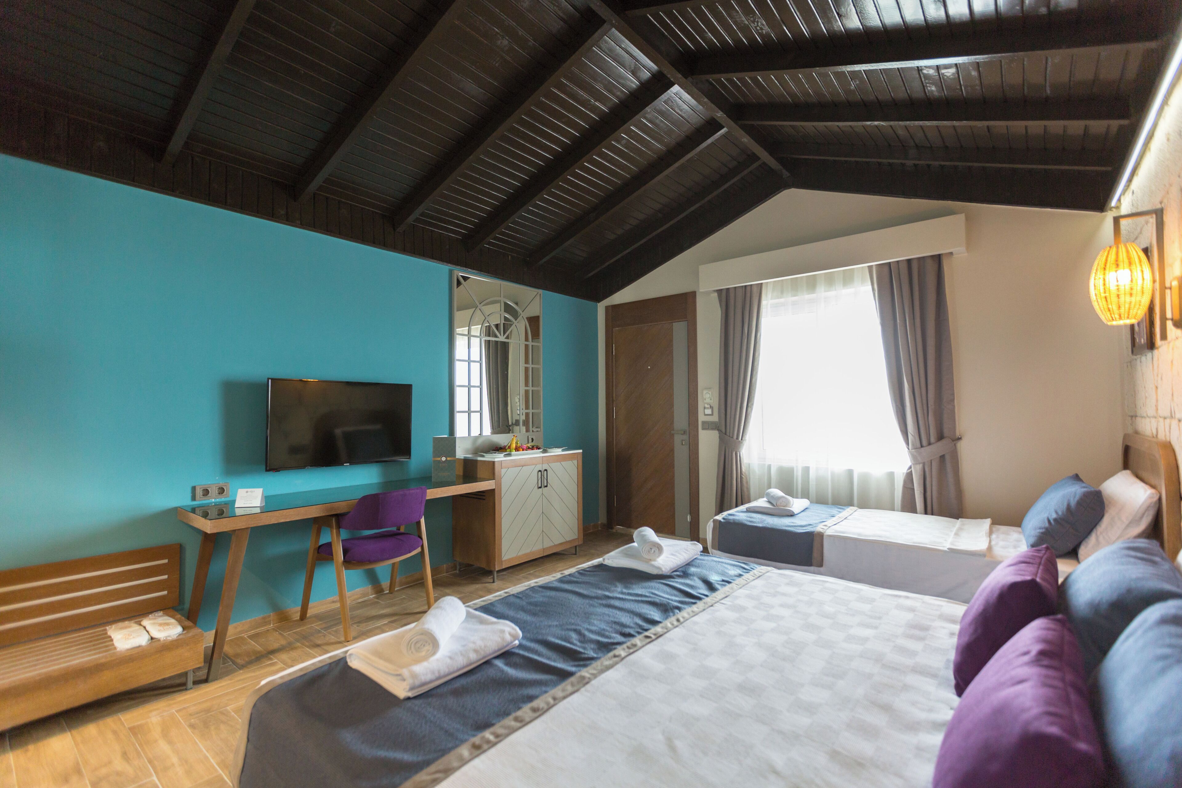 Une chambre d’hôtel équipée d’un lit, d’un bureau, d’une chaise, d’une télévision et d’une fenêtre avec des rideaux.