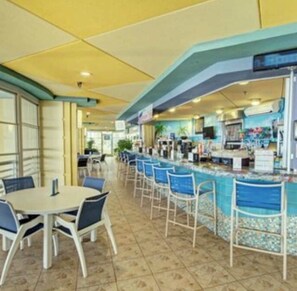 Un restaurant dotĂ© dâun espace piscine, dâun bar et de coins salon.