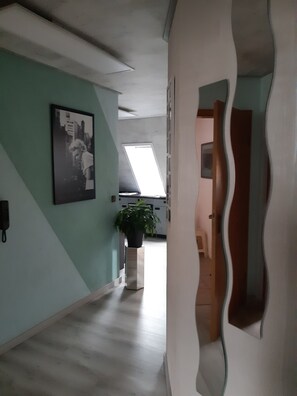 A hallway with a ceiling fan, a potted plant, a framed picture, and a door with a unique design. - Apartment 'Otto' in Nürnberg (Nuremberg)