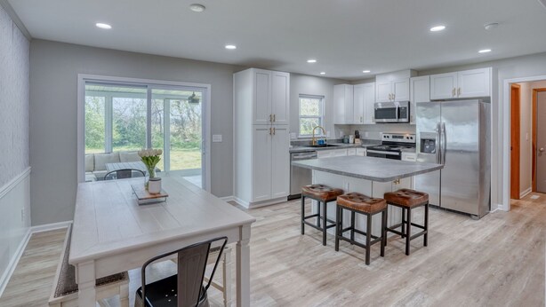 A modern kitchen with white cabinets, a stainless steel refrigerator, and a large island with stools.