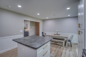A modern kitchen with a marble countertop, white cabinetry, and a geometric patterned backsplash.
