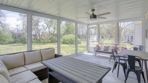 A covered patio with a cushioned seating area, a table, and chairs.