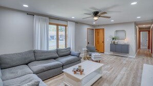 A modern living room with a grey sectional sofa, a white coffee table, a ceiling fan, and a wooden door.