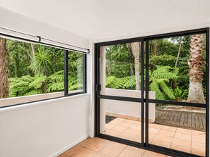A room with a sliding glass door leading to an outdoor area with a tiled floor and a wooden deck.