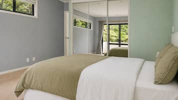 A bedroom with a bed, a window, and a door leading to another room.