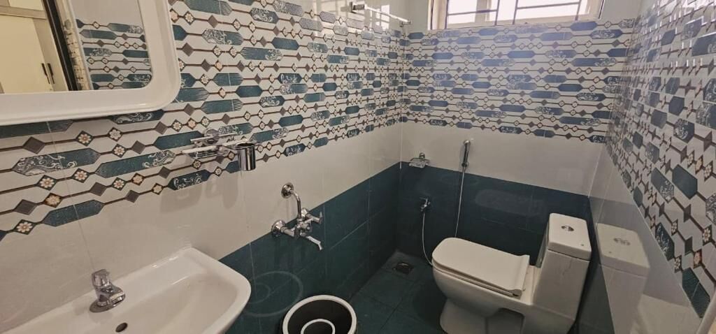 A bathroom with a sink, toilet, and shower area, featuring patterned tile walls.