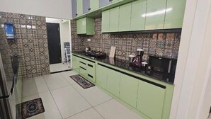 Una cucina con mobili verdi, un frigorifero, un fornello e un forno a microonde.