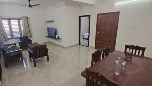 Una stanza con un tavolo da pranzo, sedie, una TV e una porta.
