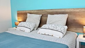 Une chambre à coucher avec une tête de lit en bois, deux lampes de chevet et une couvre-lit bleue.