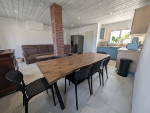 Uma cozinha moderna com mesa e cadeiras de madeira, chaminé de tijolos e um espaço de refeições com sofá.
