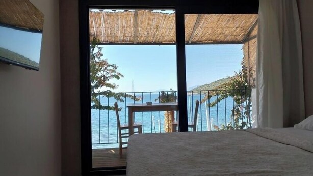 Quarto com uma janela grande que dá para uma varanda com vista para o mar.