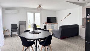 Ett modernt vardagsrum med matplats, soffa, TV och en takfläkt.