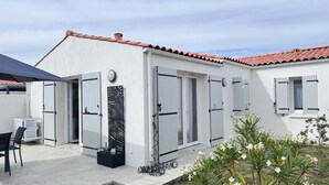 Ett modernt hus med ett tak täckt av takpannor, vita ytterväggar och fönsterluckor.