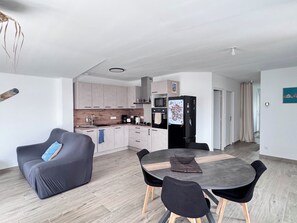 Eine moderne Küche mit Essbereich, einem schwarzen Kühlschrank und einem grauen Sofa.