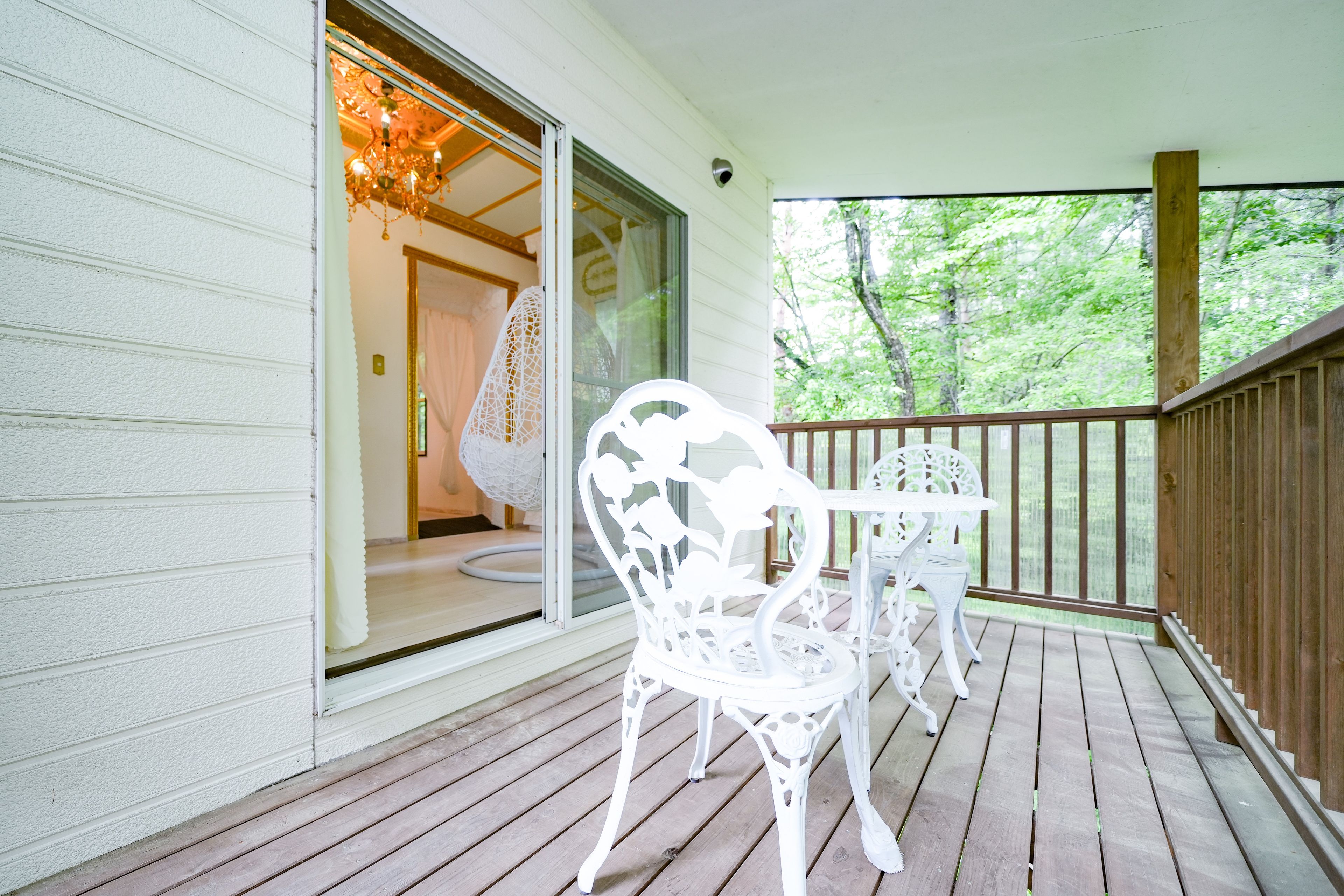 A wooden deck with white outdoor furniture, including a table and chairs.