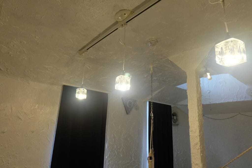 Una habitación con techo texturizado, lámparas colgantes y una puerta a la vista.