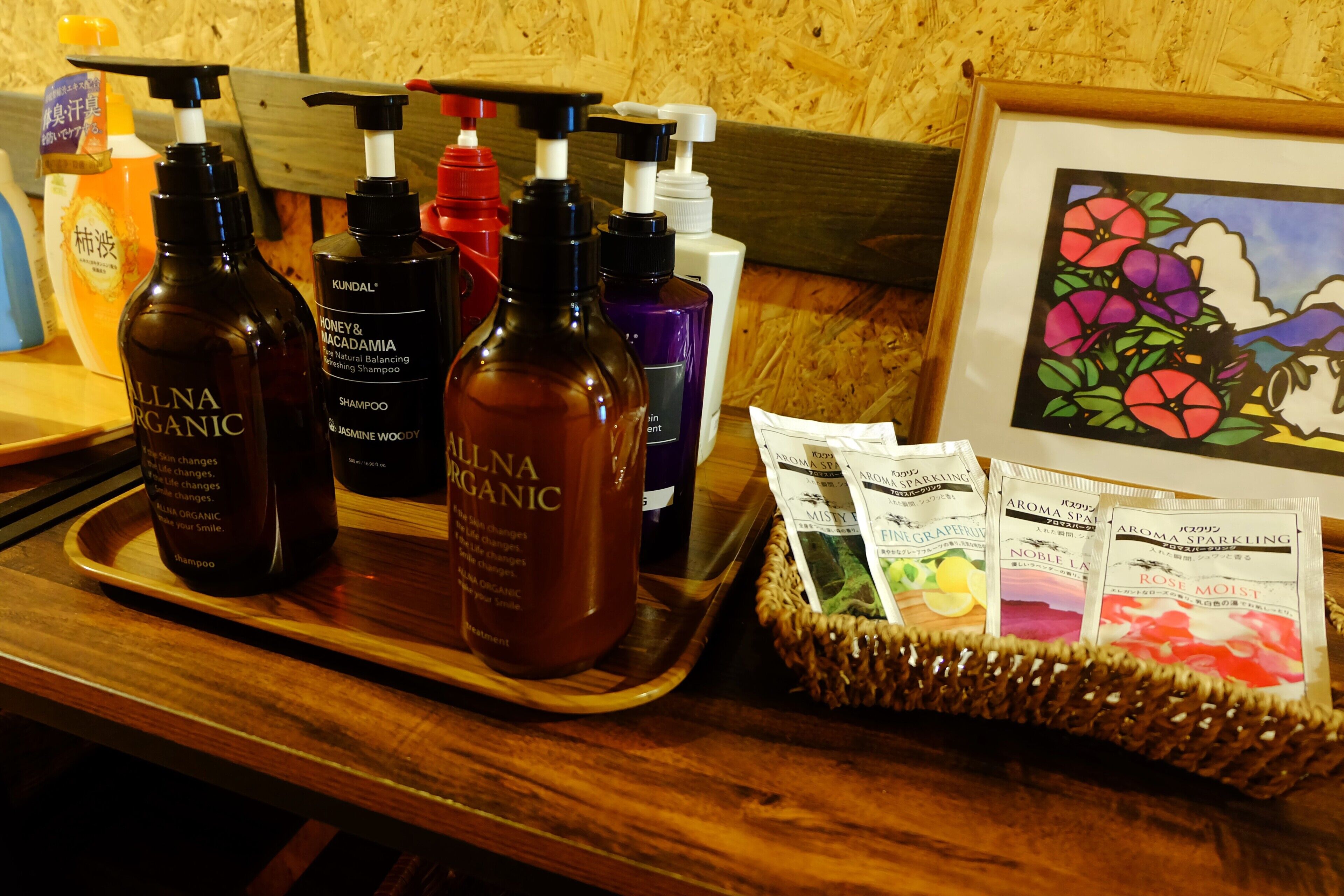 A tray with various organic shampoo bottles and a basket of scented sachets.