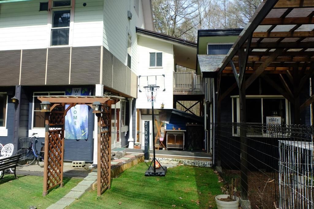 A residential property with a covered patio, a basketball hoop, and a fenced area.