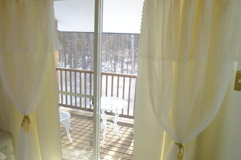 En balkon med gelænder i træ, et hvidt bord og en stol.
