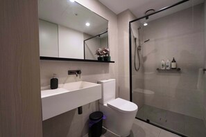 Ein modernes Badezimmer mit Duschkabine aus Glas, einem weißen Waschbecken und einer Toilette.