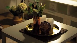 Une table avec un plateau, une lampe et une plante en pot, dans une pièce équipée d’un téléviseur à écran plat.