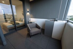 Ein moderner Balkon mit einer Couch, einem Sessel und einem kleinen Tisch.
