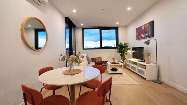 Un salon moderne comprenant un coin repas, de grandes fenêtres, un téléviseur à écran plat et une plante en pot.